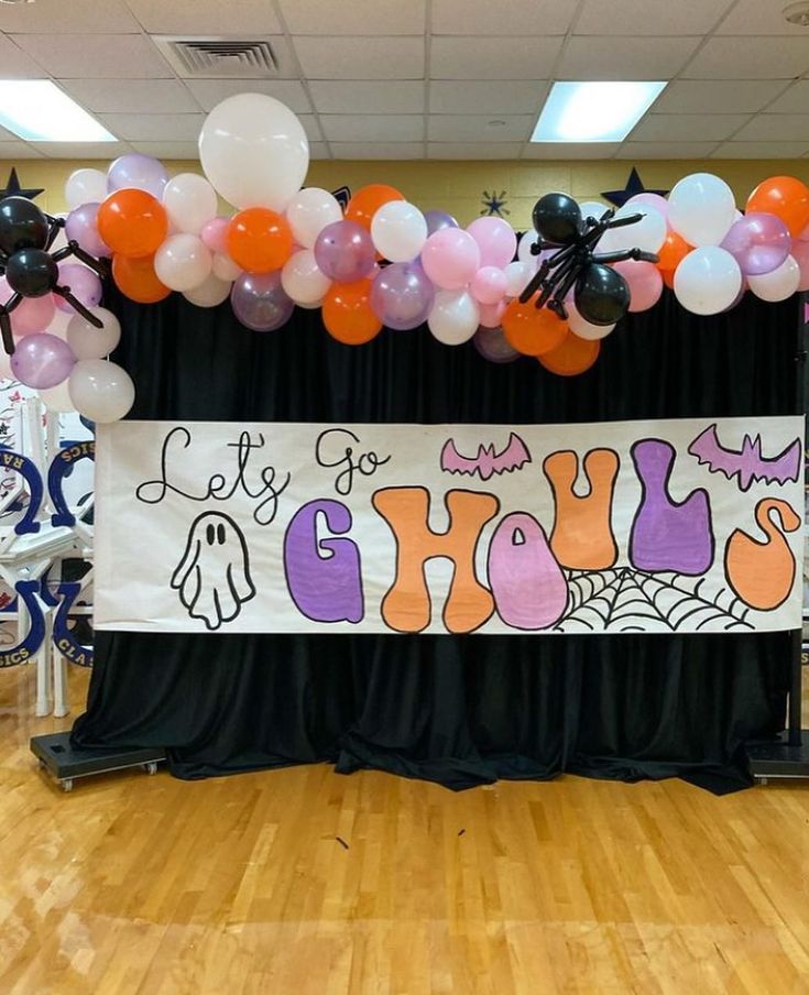 a decorated stage with balloons and decorations for a trick or treat party at the school