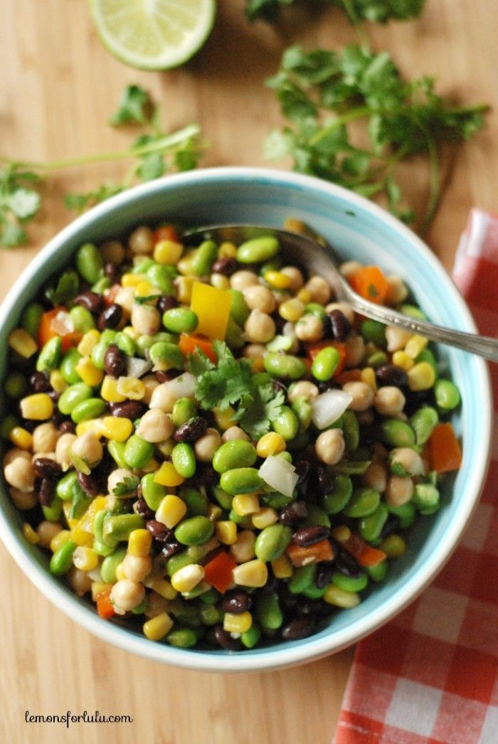 a bowl filled with beans and vegetables on top of a wooden table