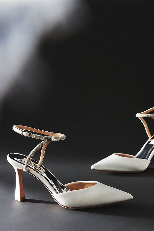 a pair of white high heeled shoes sitting on top of a black table next to each other