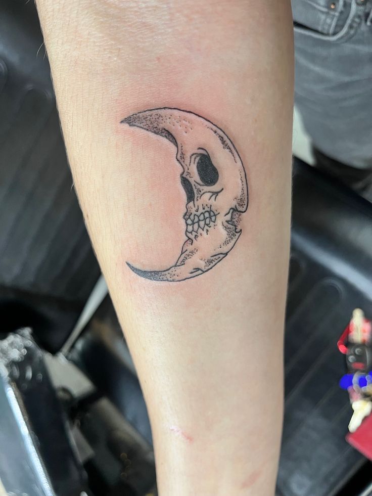 a person with a small tattoo on their arm that has a skull in the moon