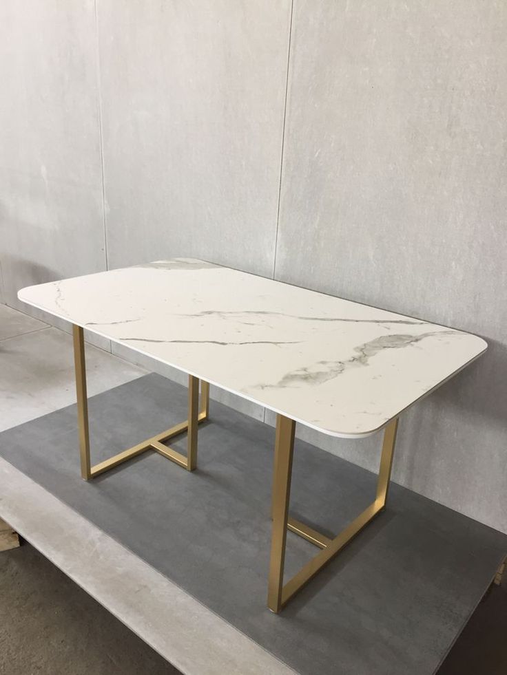 a white marble table with gold legs on display in a storeroom or office space