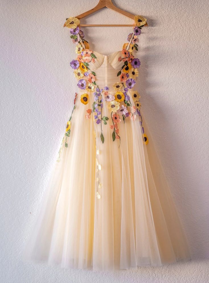 Adorned with a vibrant array of hand-stitched florals that cascade over the bodice, this homecoming dress is a garden of enchantment. Its plunging V-neckline is both bold and delicate, leading to a flowing tulle skirt that falls gently to the floor. The warm, creamy base of the dress is a canvas for the embroidered blossoms, presenting a stunning array of springtime hues that will make you the belle of the ball. From the soft pastel petals to the intricate greenery, every detail sings a melody of naturebeauty. This dress isn't just an outfit; ita statement of grace, a wearable work of art for a night filled with magic. Colorful Homecoming Dresses, Champagne Homecoming Dresses, Tea Length Prom Dress, Flower Tulle, Tulle Party Dress, Tulle Homecoming Dress, Tulle Sleeves, Short Prom Dress, Sweet 16 Dresses