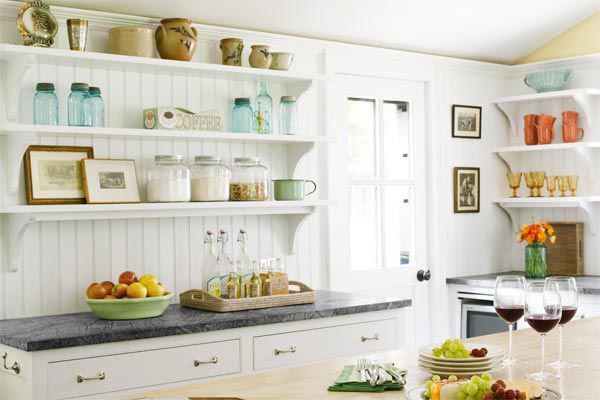 a kitchen filled with lots of white cabinets and counter top next to a wine glass holder