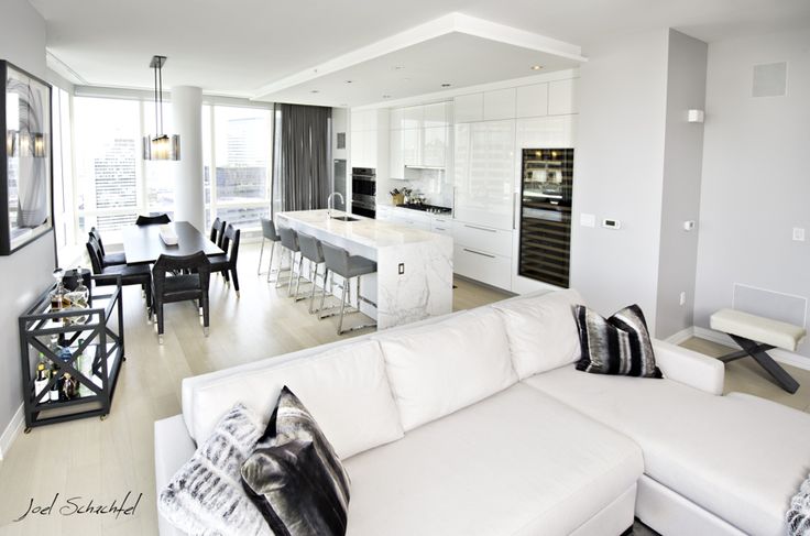 a living room filled with furniture next to a kitchen and dining room table in front of a large window