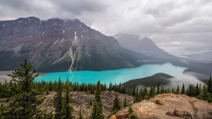 a view of a mountain lake from the top of a hill with trees around it