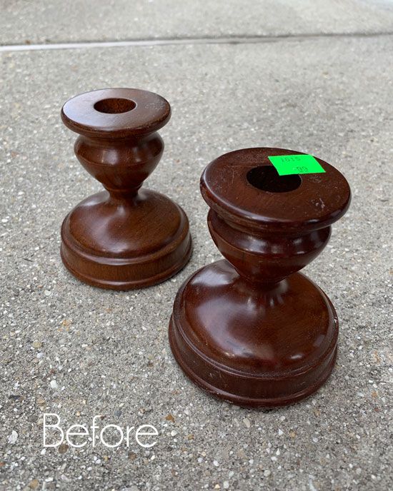 two brown wooden candlesticks sitting on top of a cement ground next to each other