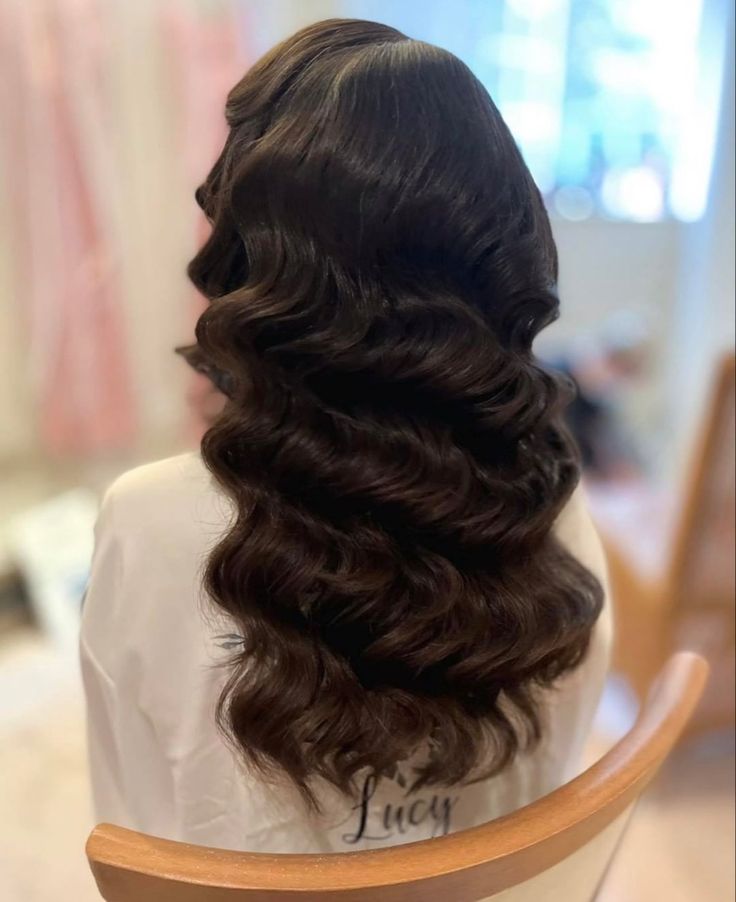 the back of a woman's head with curly hair in it and an inscription on her chest