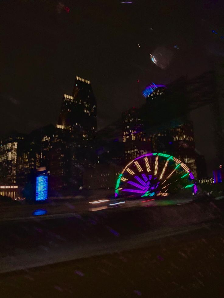 a ferris wheel lit up at night in the city