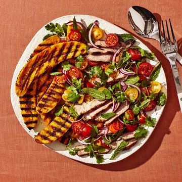 a plate with grilled chicken and vegetables on it next to a fork and knife