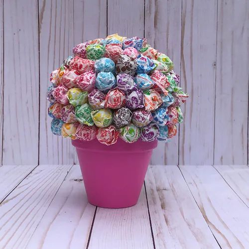 a pink pot filled with lots of colorful candies on top of a wooden table