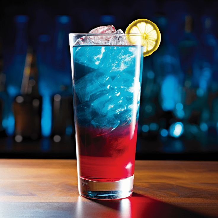 a tall glass filled with blue and red liquid next to a slice of lemon on top of a wooden table