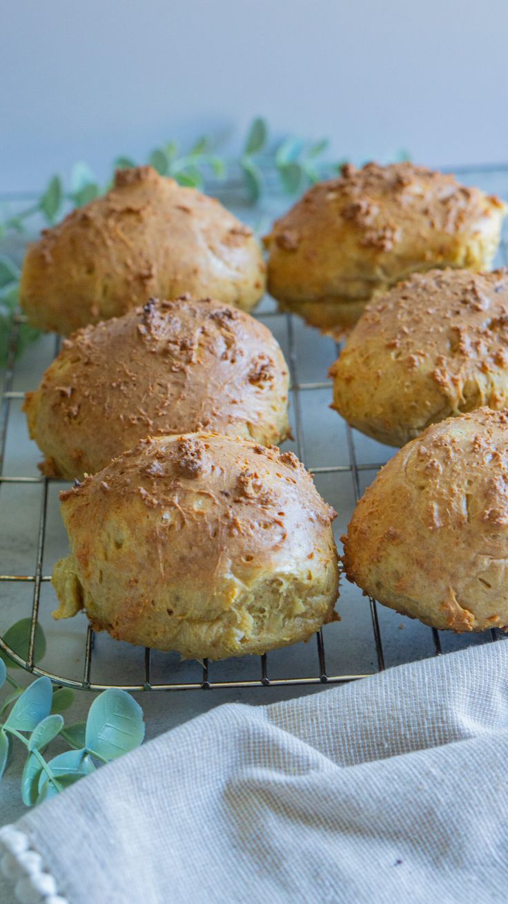 six freshly baked muffins cooling on a wire rack with green leaves around them