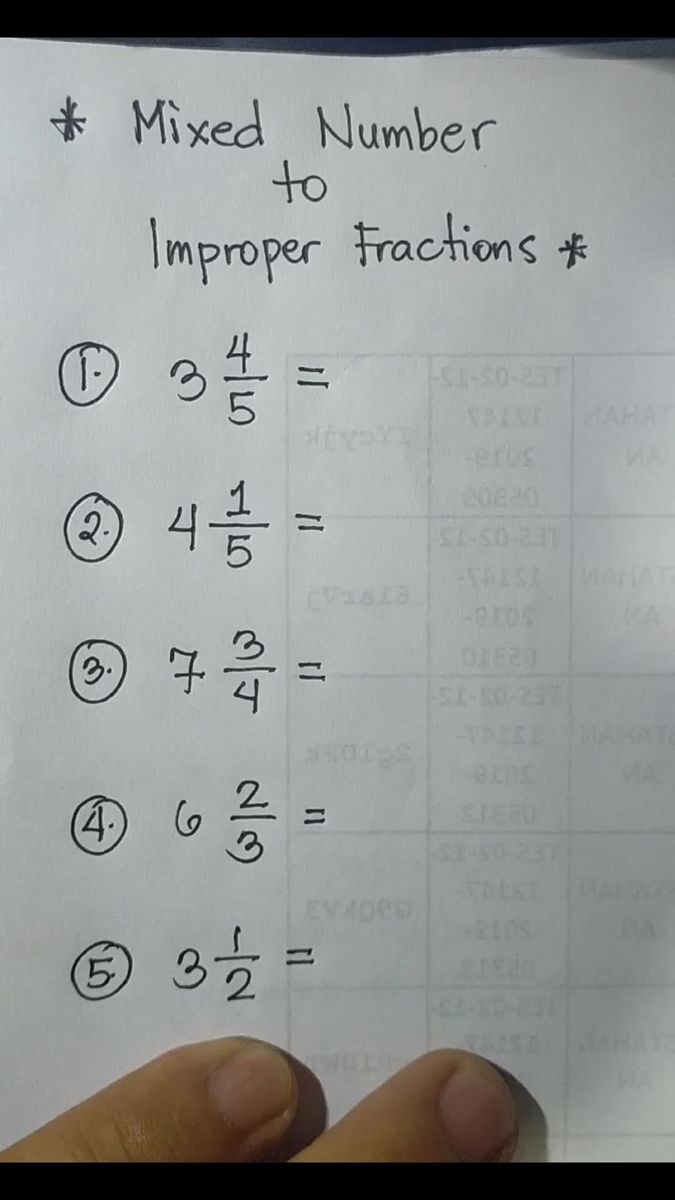 a hand holding up a piece of paper with numbers and fractions written on it