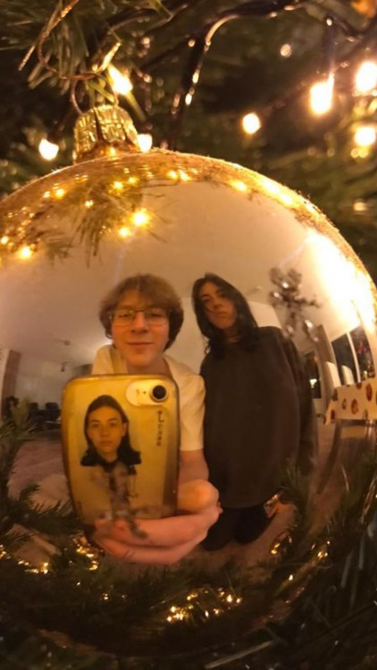 two women standing in front of a christmas ornament with an image of them