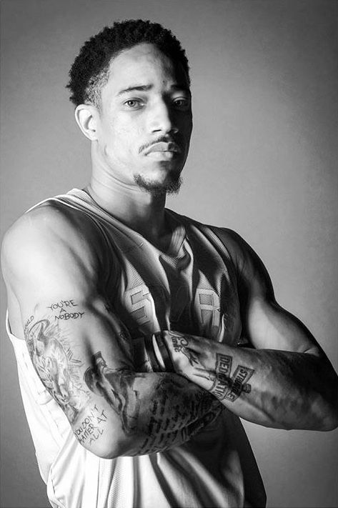 a man with tattoos on his arm and arms crossed, posing for the camera in black and white