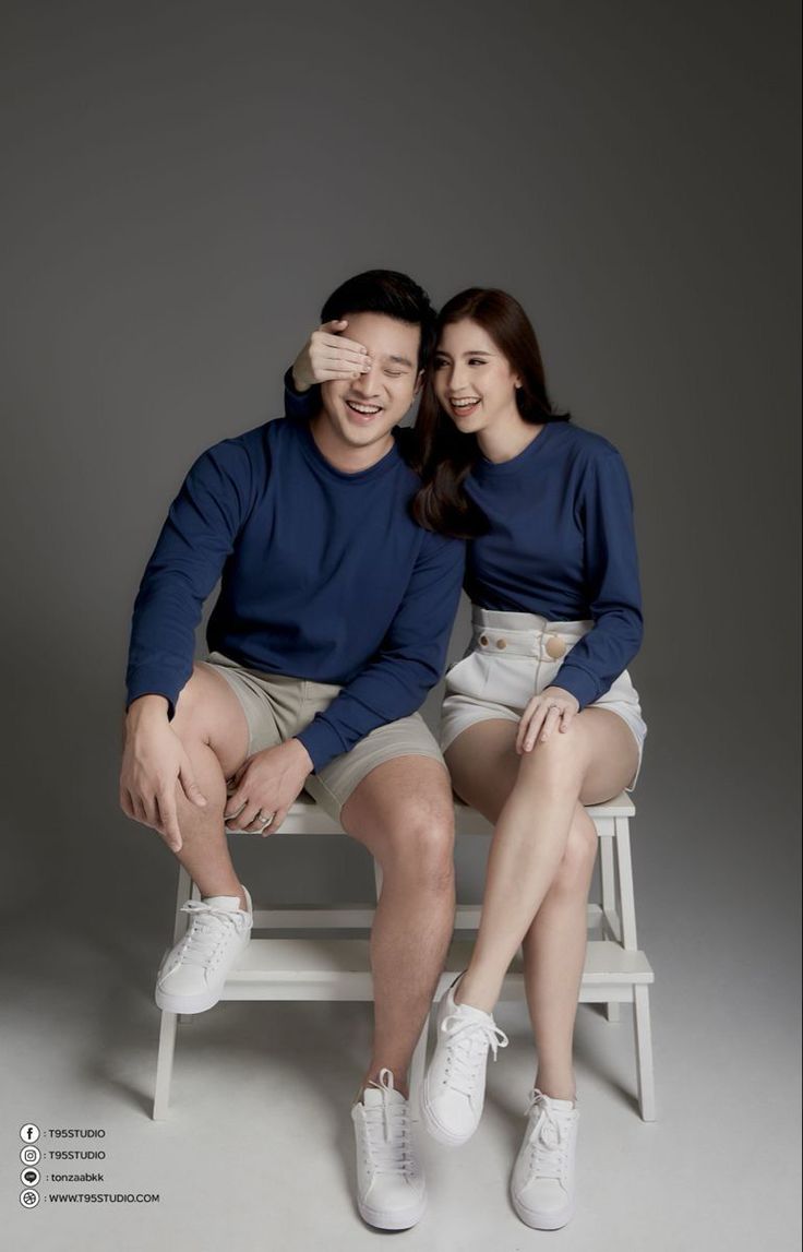 a man and woman sitting on a white chair together smiling at the camera with their arms around each other