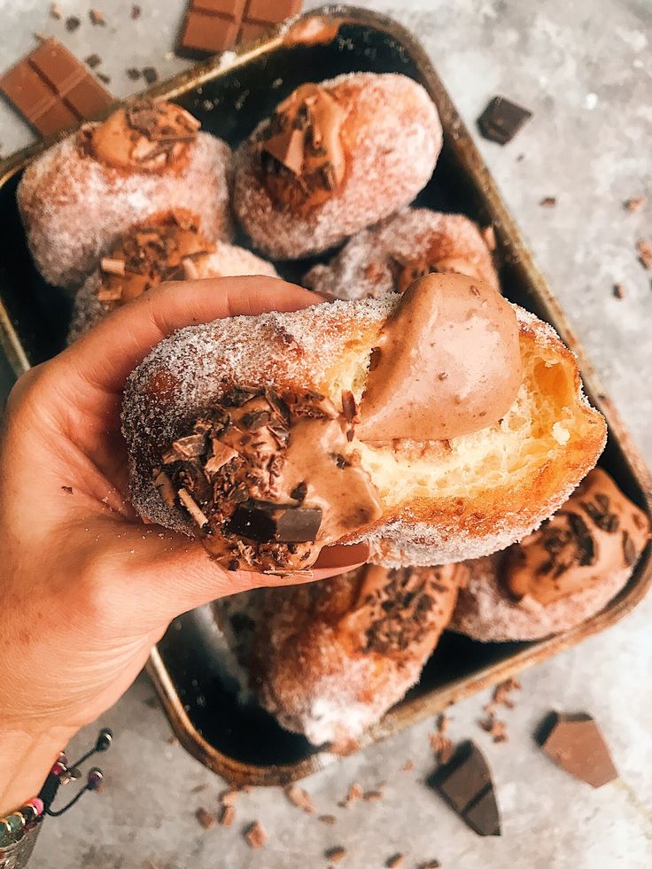 a person holding up a half eaten doughnut in front of chocolate chunks and other pastries