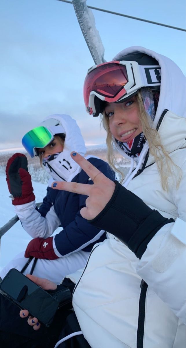 two women and a child sitting on a ski lift in the snow with their fingers up