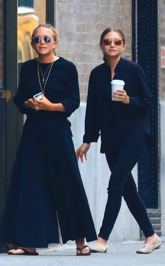 two women walking down the street while holding coffee