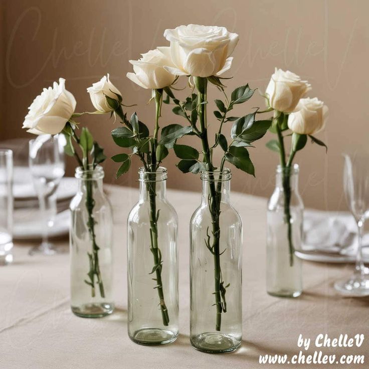 four vases with white roses in them on a table