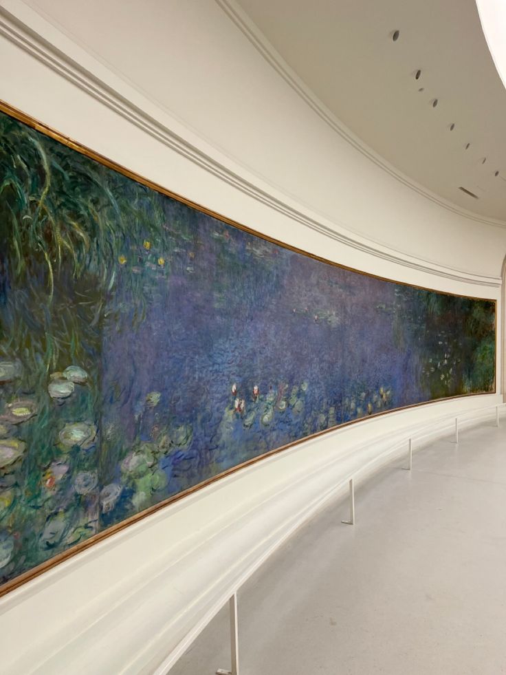 a large painting hanging on the side of a wall next to a long white hallway