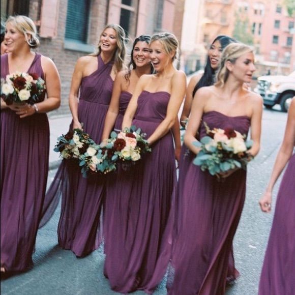 a group of women in purple dresses standing next to each other