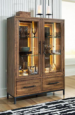 a tall wooden cabinet with glass doors and drawers on top of it next to a rug