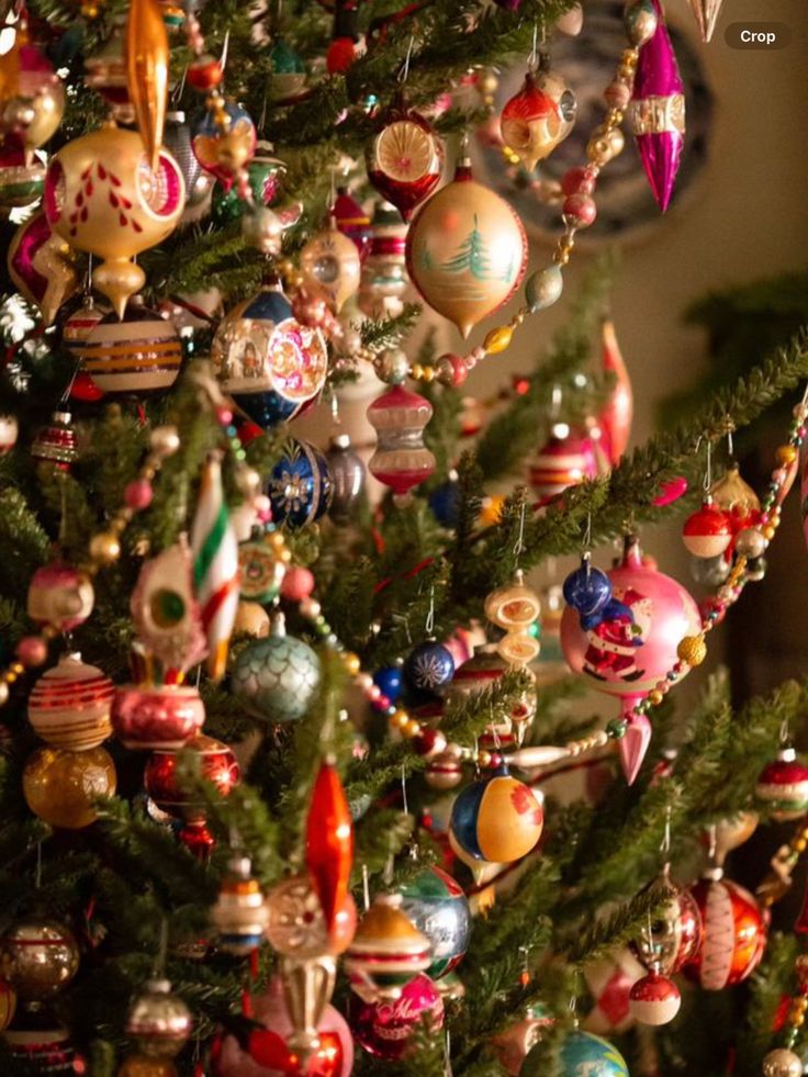 a christmas tree with many ornaments hanging from it's branches and decorations on the top