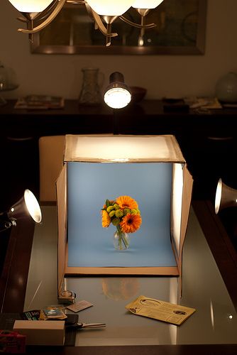 a vase with flowers in it sitting on a table next to two lights and a mirror