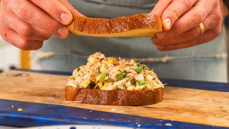 a person holding a piece of bread with food on it