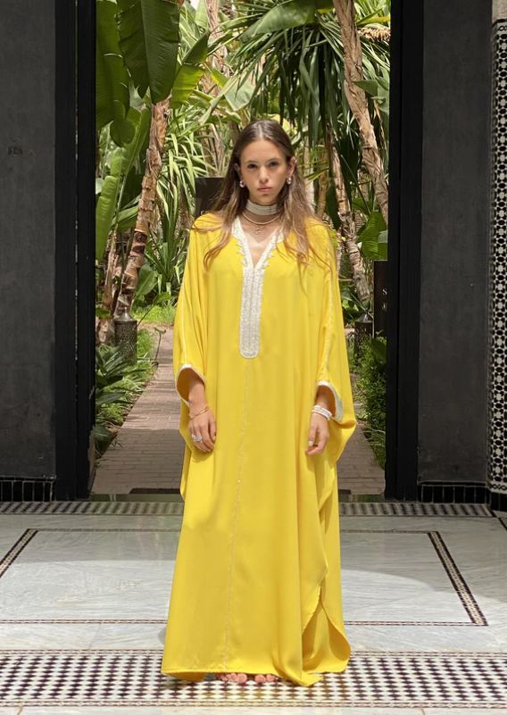 Illuminate your style with our Crepe Oversized Kaftan in the radiant Yellow color. This kaftan beautifully combines tradition and modernity, showcasing the artistry of Moroccan craftsmanship.   Product Details:      V-Neck Kaftan with Handmade "Sfeefa" Finish : The Crepe Oversized Kaftan features an elegant V-neck design adorned with our signature handmade "sfeefa" for a touch of Moroccan opulence.     Handmade Embroideries : Delicate handmade embroideries grace the neckline and front of this ka Festive Floor-length Yellow Kaftan, Bohemian Abaya With Traditional Drape, Traditional Yellow Kaftan For Eid, Elegant Traditional Drape Kaftan For Spring, Yellow Bohemian Kaftan For Festive Season, Yellow Bohemian Kaftan For Festive Occasions, Elegant Yellow Kaftan For Eid, Festive Yellow Bohemian Kaftan, Festive Bohemian Yellow Kaftan