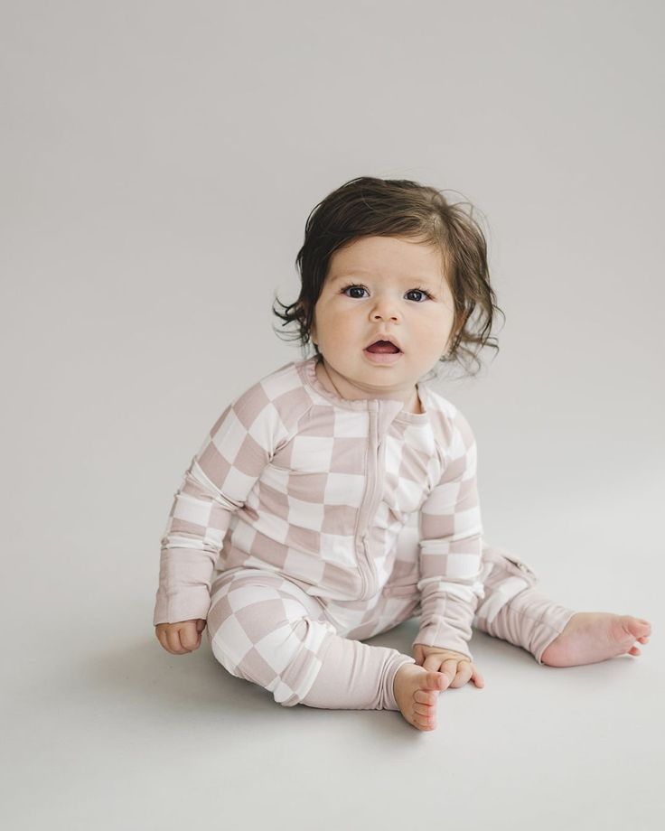 Embrace the cuteness and comfort with our Latte Checkered Bamboo Zip Baby Jumpsuit. Designed for your little one’s all-day comfort, this jumpsuit is ultra-soft and stretchy, perfect for playtime, nap time, or any cozy cuddle time. Made from 95% bamboo viscose and 5% spandex, it features practical fold-over mittens and footies for sizes up to 12-18 months, ensuring your baby’s hands and feet stay warm. The two-way zipper simplifies diaper changes, making it convenient for parents while keeping ba Playful Fitted Jumpsuits And Rompers For Loungewear, Playful Long-sleeve Bubble Romper For Loungewear, Playful Long Sleeve Bubble Romper For Loungewear, Super Soft Long Sleeve Onesie For Playtime, Soft Fitted Onesie For Playtime, Playful Long Sleeve Bodysuit For Bedtime, Playful Pink Bodysuit For Loungewear, Super Soft White Onesie For Playtime, Cute Long Sleeve Bodysuit For Bedtime