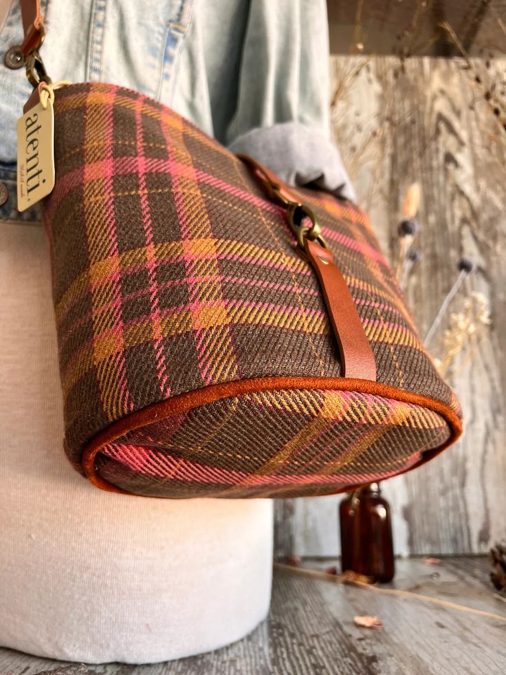 This seamless and intricate tartan plaid is woven into the fabric and is just perfect for those crisp walks in the autumn air.

The Atenti Scottie Halle Bucket Bag features two interior pockets, leather detachable adjustable crossbody strap, and a leather closure. Halle measures: 8″ wide x 8″ high x 5.5″ deep. Fall Leather Trim Crossbody Shoulder Bag, Fall Shoulder Bag With Leather Trim, Crossbody Shape, Wool Travel Bags For Fall, Fall Leather Trim Satchel Shoulder Bag, Fall Bags With Brass Hardware, Fall Woven Shoulder Bag For Daily Use, Fall Satchel Shoulder Bag With Leather Trim, Woven Shoulder Bag For Daily Use In Fall, Everyday Bags With Brass Hardware For Fall