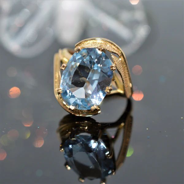 A ladies 14 karat yellow gold leaf design ring set with an oval cut blue topaz.  The ring is size 5.75 Formal Oval Blue Topaz Birthstone Ring, Blue Oval Topaz Ring In 14k Gold, Oval Blue Topaz Ring In 14k Gold, Fine Jewelry Light Blue Oval Topaz Ring, Classic Oval Topaz Birthstone Ring, Classic Oval Topaz Ring, Oval Blue Topaz Ring In Fine Jewelry Style, Oval Blue Topaz Ring Fine Jewelry, Fine Jewelry Oval Blue Topaz Ring