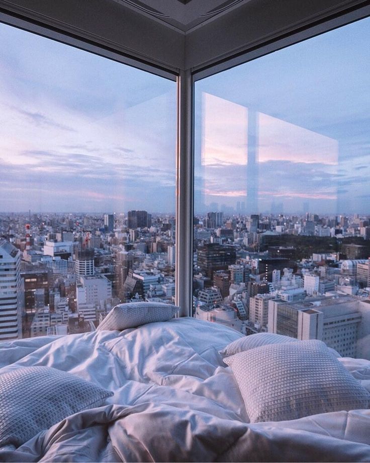 a bed in front of a window overlooking the city