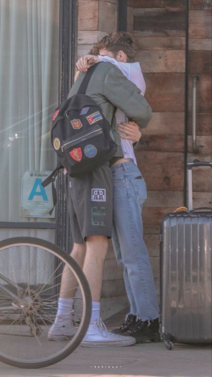 two people hugging each other in front of a building next to a bike and bicycle