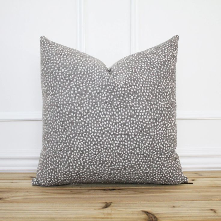 a gray and white pillow sitting on top of a wooden floor