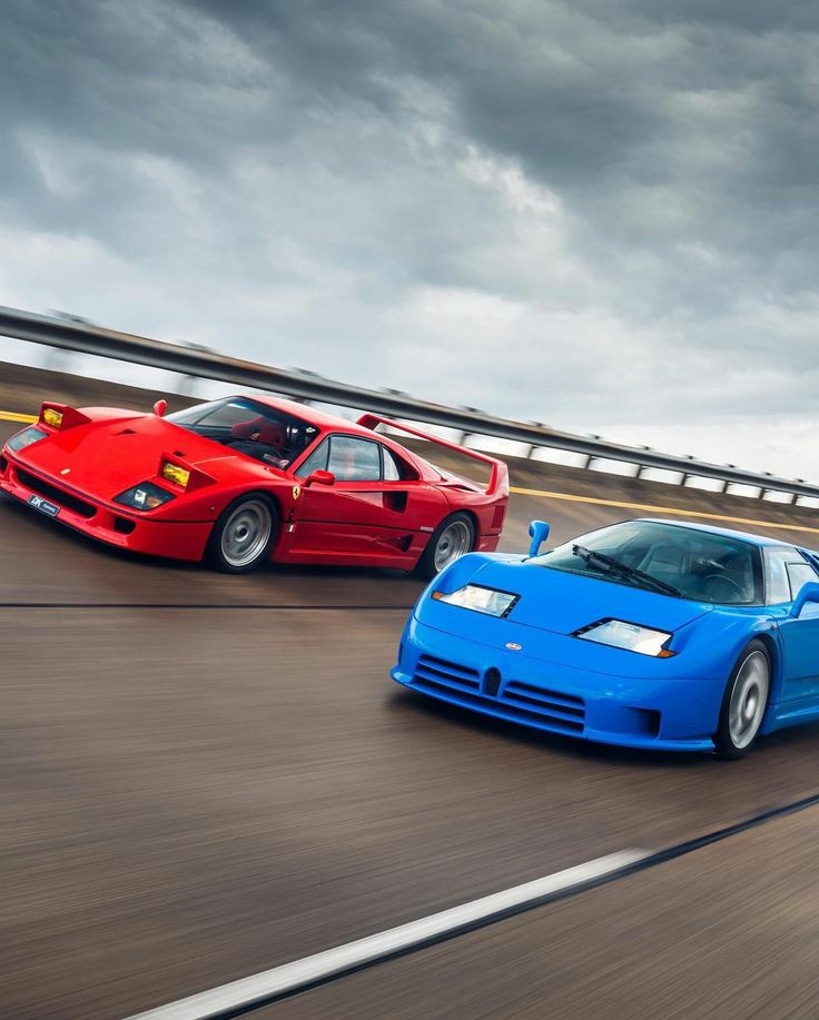 two sports cars driving down the road in front of each other on a cloudy day