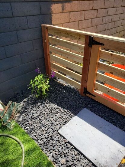 a small garden area with gravel, rocks and wooden slats on the side of a building