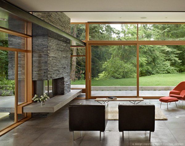 a living room filled with furniture next to a fire place and large windows that look out onto a lush green field