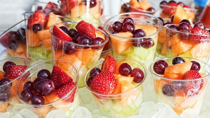 several cups filled with different types of fruit on top of ice cubes and garnishes