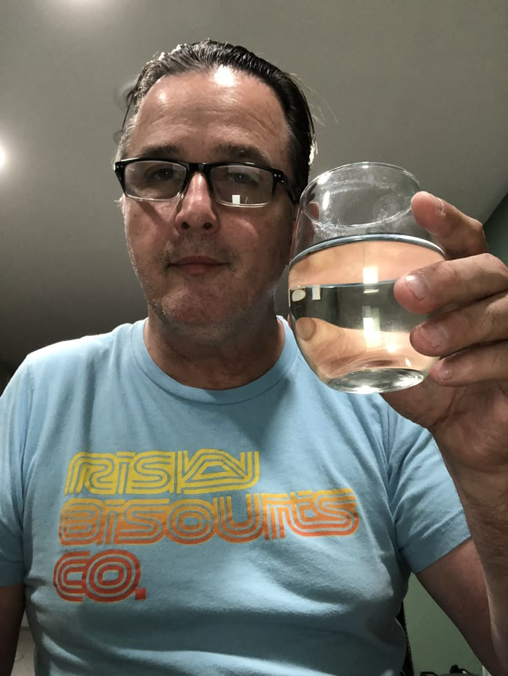 a man holding up a glass with water in it