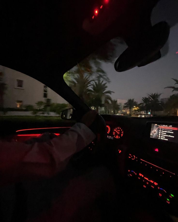 the interior of a car is lit up with red lights and palm trees in the background