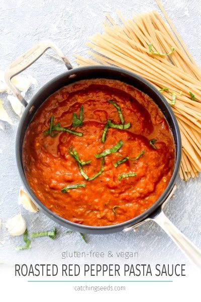 a pan filled with red pepper sauce next to pasta