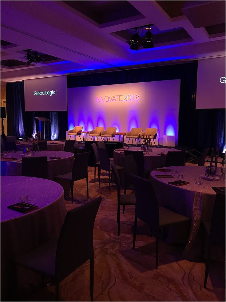 an empty banquet room with round tables and purple lighting