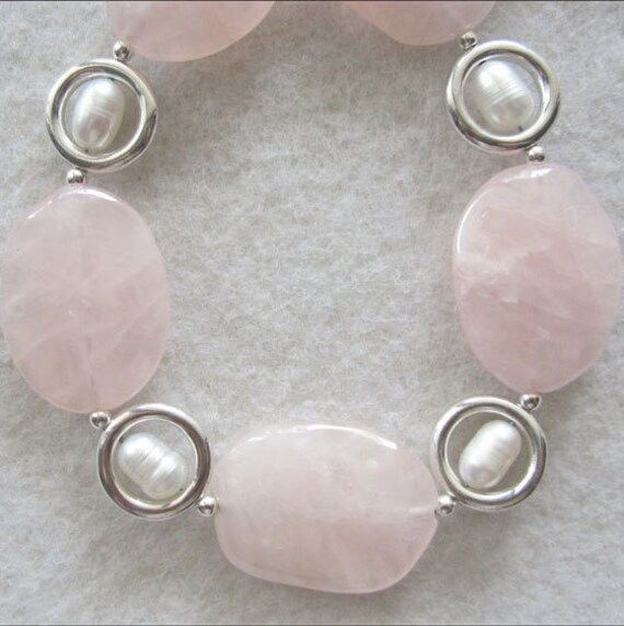 Each Rose Quartz stone in this pretty and delicate necklace is cut like a rose petal and ranges from clear to translucent. The color is a lovely very light pink to soft rose. Designed and handcrafted by Miriam with Sterling Silver rings and white Freshwater Pearls. The shiny silver rings reflect the rosy pink stone color onto the pearls creating an iridescent glow. Rose Quartz is the rosy pink variety of Quartz, which comes in a rainbow of colors as well as crystal clear. The pink to rose red co Pink Oval Feminine Jewelry, Feminine Oval Pink Jewelry, Feminine Pink Oval Jewelry, Elegant Rose Quartz Jewelry With Natural Stones, White Rose Quartz Jewelry For Jewelry Making, Elegant Rose Quartz For Jewelry Making, Feminine Rose Quartz Wedding Jewelry, Delicate Rose Quartz Jewelry For Wedding, Elegant Rose Quartz Round Jewelry