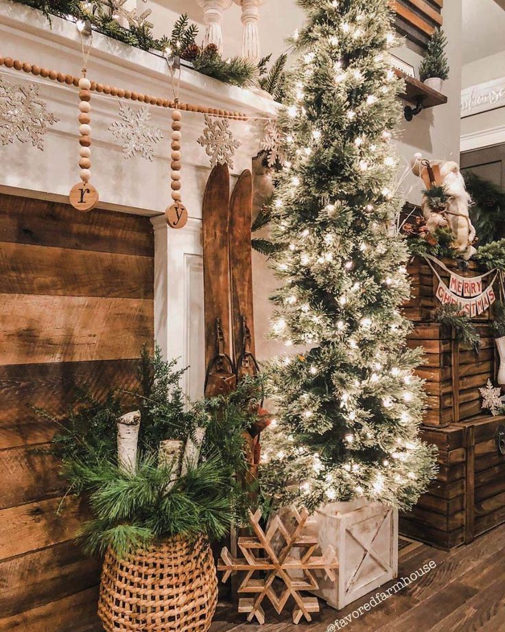 a christmas tree in front of a fireplace decorated with garlands and snowflakes