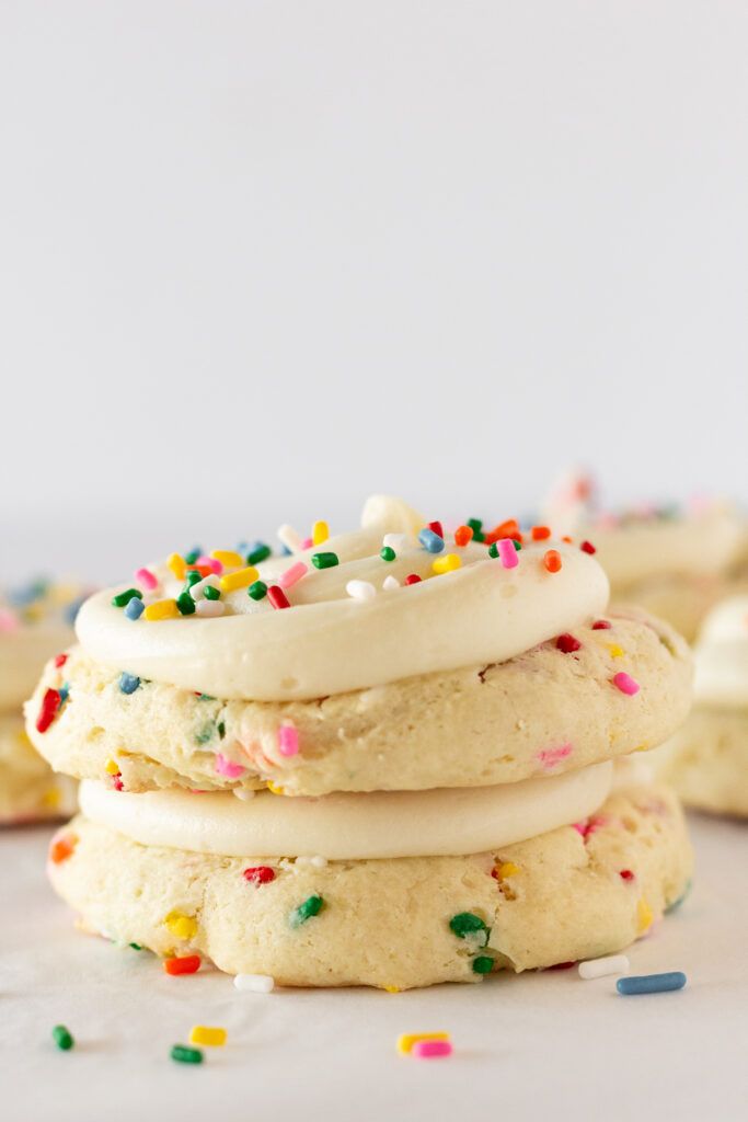 a stack of cookies with white frosting and sprinkles