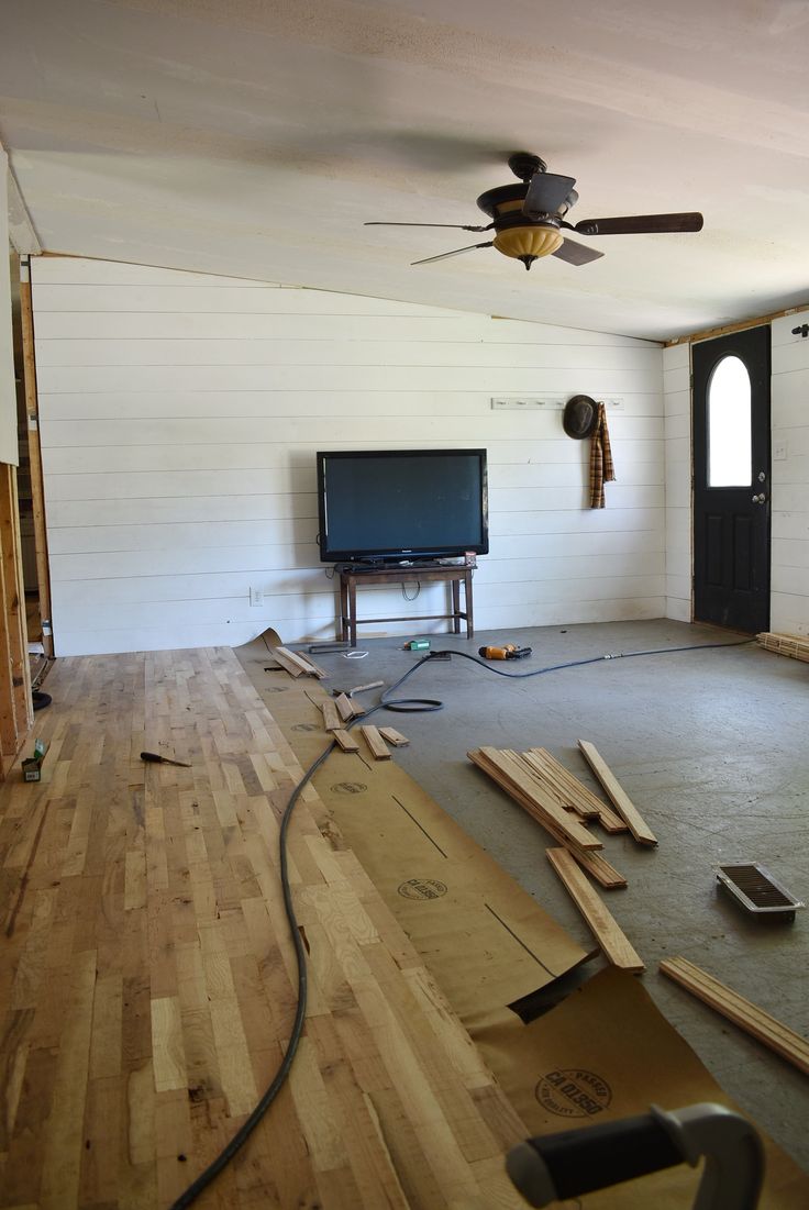 a living room with hard wood flooring and a ceiling fan in the middle of it