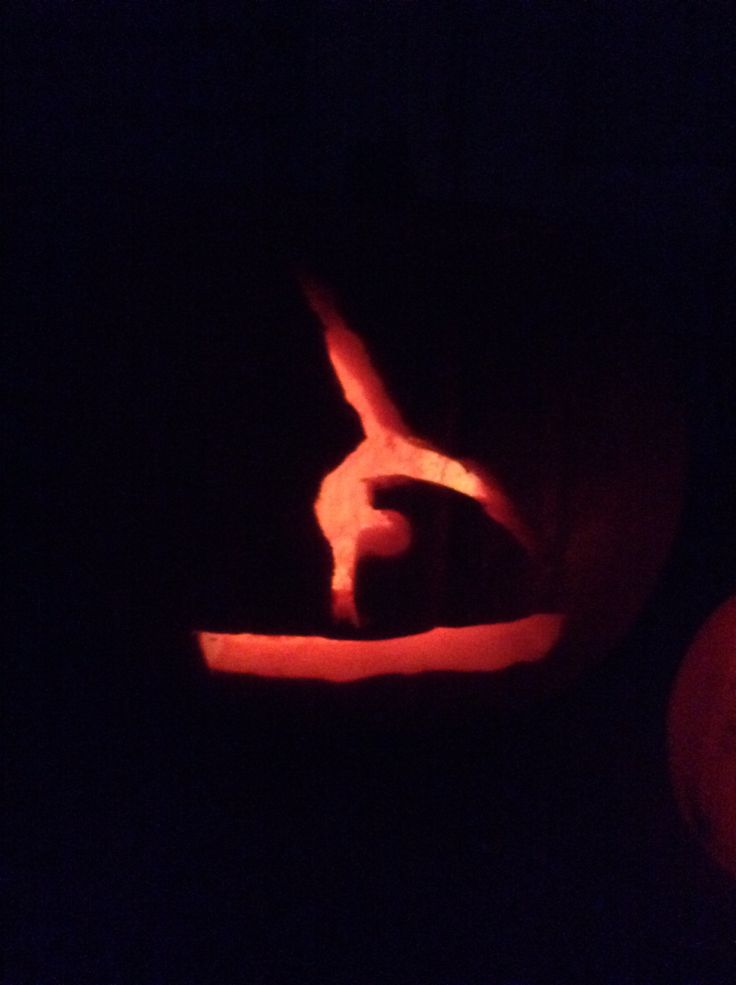 a pumpkin carved to look like a person doing a handstand in the dark